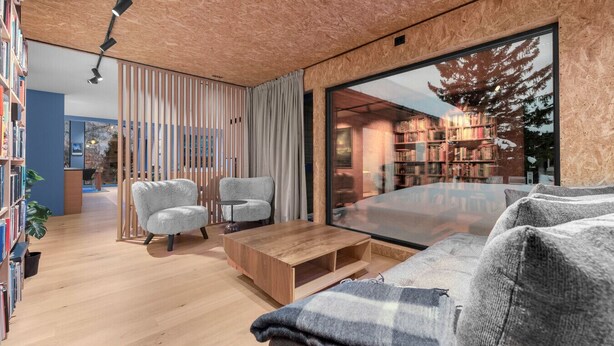 Ein modernes Wohnzimmer mit Holzboden, Glaswand und Bücherregal.
