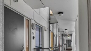 Ein Korridor mit Türen, einem Geländer und einem Holzboden.