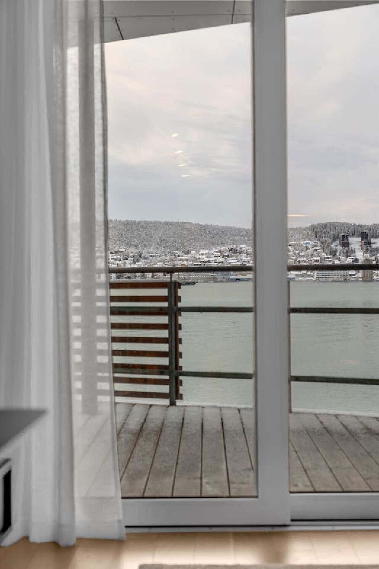 A view from a balcony with a wooden floor, a metal railing, and a glass door.