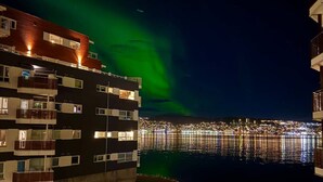 Ein Gebäude am Wasser mit Balkonen und Blick auf die Stadtlichter.