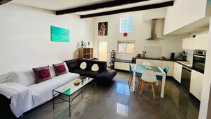 A modern living room with a sofa, coffee table, and a dining area with chairs and a table. - "La Plagette" Baraquette near Etang, Clim (Sète)