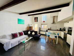 A modern living room with a sofa, coffee table, and a dining area with chairs and a table. - "La Plagette" Baraquette near Etang, Clim (Sète)