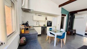 A compact kitchen with a dining area, a built-in oven, and a window. - "La Plagette" Baraquette near Etang, Clim (Sète)