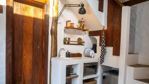A rustic kitchen with a wooden door, a shelf with jars, a kettle, and a hanging cloth. - Villaggio Serra da Cantareira (Mairiporã)
