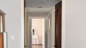 Un pasillo con un tapete a rayas, una puerta de madera y una pared blanca.