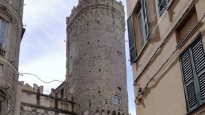 Una torre de piedra histórica, una camioneta blanca y un edificio con un letrero que dice 'Bar d'Oro'.