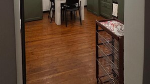 Una cocina compacta con una mesa y sillas, piso de madera y muebles de cocina color verde.