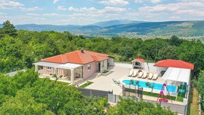 A villa with a swimming pool, a covered patio, and a view of the surrounding hills. - Villa Korana with heated Pool and Jacuzzi (Kamenmost)