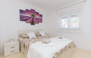 A bedroom with a bed, a nightstand, a window with curtains, and a wall-mounted artwork. - Villa Korana with heated Pool and Jacuzzi (Kamenmost)