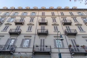 A multi-story building with balconies, windows with shutters, and a street lamp.