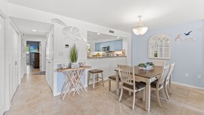 Eine moderne Küche mit blauen Schränken, ein Essbereich mit einem Holztisch und Stühlen sowie ein Kronleuchter.