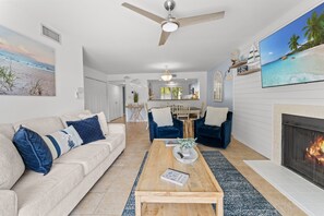 Ein Wohnzimmer mit Sofa, Couchtisch, Kamin und einem an der Wand befestigten Fernseher.