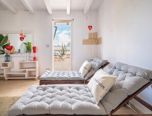 Ein modernes Wohnzimmer mit einer Couch, einem Couchtisch und einem Essbereich, der durch eine Glastür sichtbar ist.