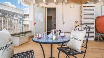 A patio with a round table, two chairs, a yellow umbrella, and a white bag with text.