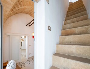A staircase with stone steps leading to a room with a white door and a tiled floor. - Petra Domus Spa & Private Lodge (Veglie)