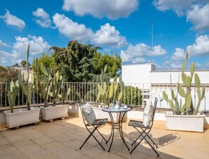 A rooftop terrace with potted cacti, a round table, and two chairs. - Petra Domus Spa & Private Lodge (Veglie)