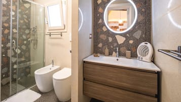 Un baño con cabina de ducha de vidrio, un lavamanos con espejo y un inodoro.