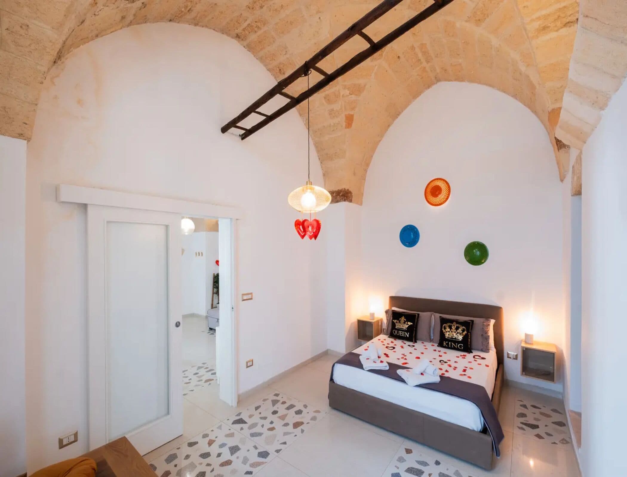 Une chambre à coucher avec un lit, une échelle, une porte et un mur décoré d’assiettes.