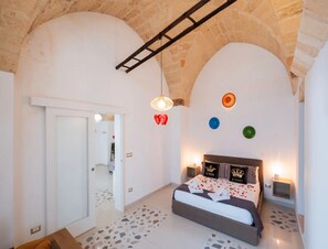 Ein Schlafzimmer mit einem Bett, einer Leiter, einer Tür und einer Wand mit dekorativen Tellern.