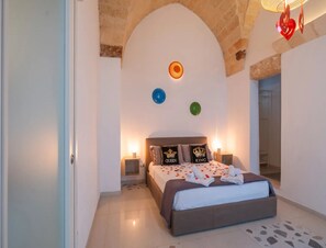 A bedroom with a bed, two bedside tables, a wall clock, and a mirror. - Petra Domus Spa & Private Lodge (Veglie)