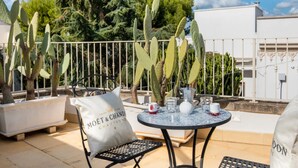 A terrace with a table set for two, surrounded by cacti, a white fence, and a building in the background. - Petra Domus Spa & Private Lodge (Veglie)