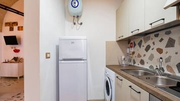 A compact kitchen with a washing machine, a refrigerator, and a water heater.