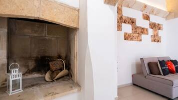 Una chimenea con detalles de piedra, un farol blanco y un sofá gris con cojines.