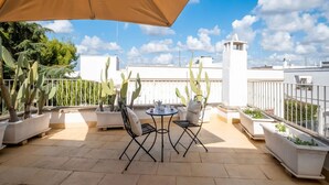 A terrace with a table and chairs, potted plants, and a white building in the background. - Petra Domus Spa & Private Lodge (Veglie)