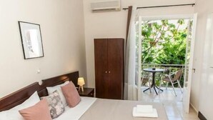 A hotel room with a bed, a nightstand, a wardrobe, and a balcony with a table and chairs. - Hotel Thetis (Tolo)