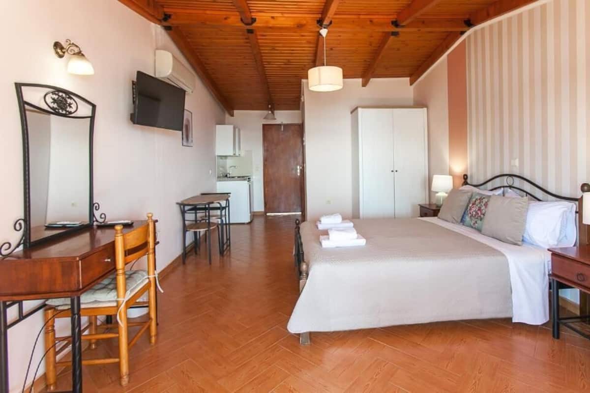 A bedroom with a bed, bedside table, lamp, and a desk with a chair.
