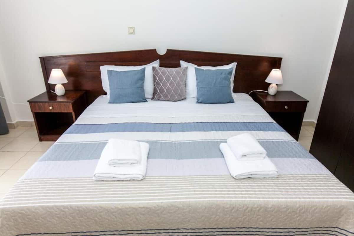 A neatly made bed with striped bedding, two bedside lamps, and a headboard.
