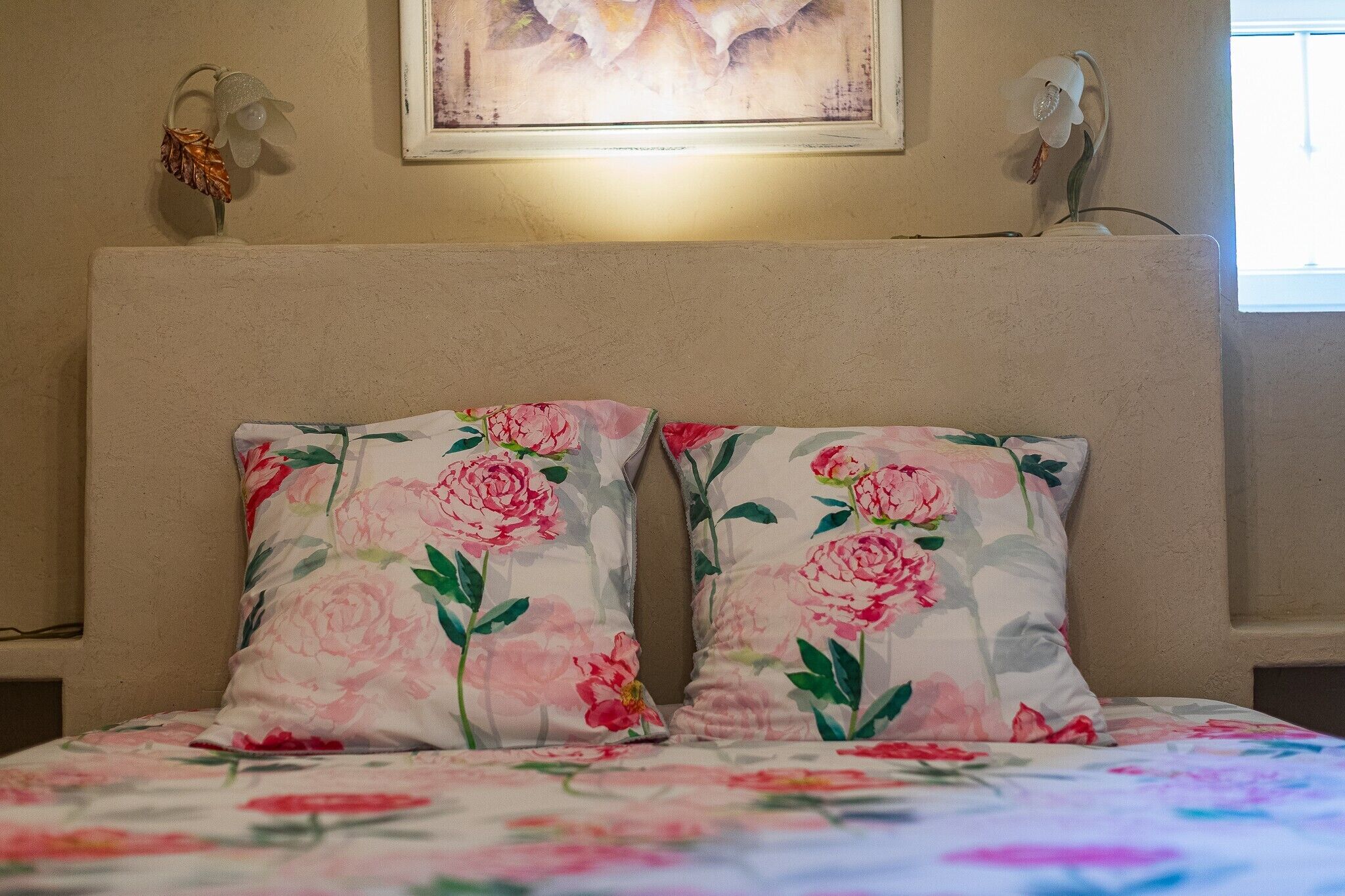 Uma cama com almofadas estampadas e uma obra de arte emoldurada acima.