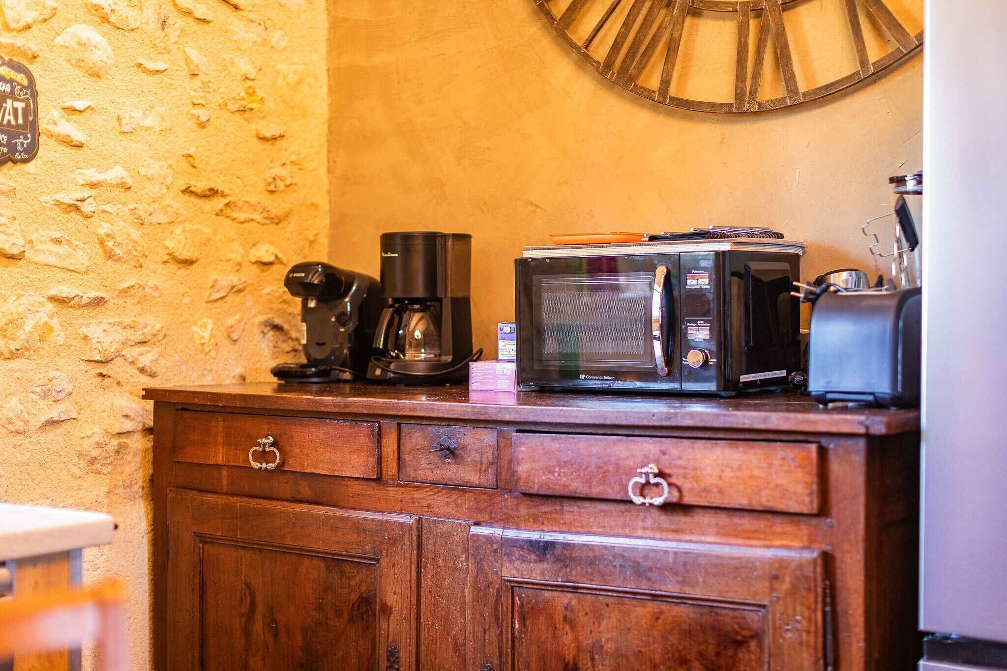 Een kitchenette met een koffiezetapparaat, magnetron en broodrooster op een houten kast.