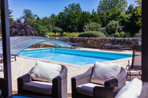Une piscine avec des chaises longues et un mur en pierre.