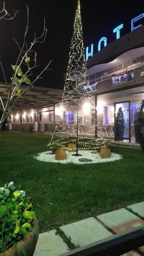 A hotel with a large Christmas tree decorated with lights in the courtyard.