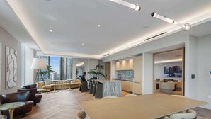 A modern living room with a large wooden table, sofas, and a kitchen area. - Urban 1BR+Den | Gym | Spa | Downtown Miami (Miami)