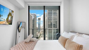 A bedroom with a large window, a bed, a bedside table, and a wall-mounted TV. - Urban 1BR+Den | Gym | Spa | Downtown Miami (Miami)