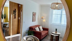 Un soggiorno con un divano rosso, uno specchio con cornice in legno, un tavolino con una lampada e una pianta in vaso.