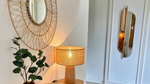 Un tavolo consolle in legno con una lampada, uno specchio e un vaso con piante verdi.