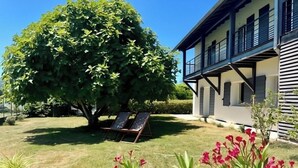 Una casa con un grande albero, un prato e due poltrone.