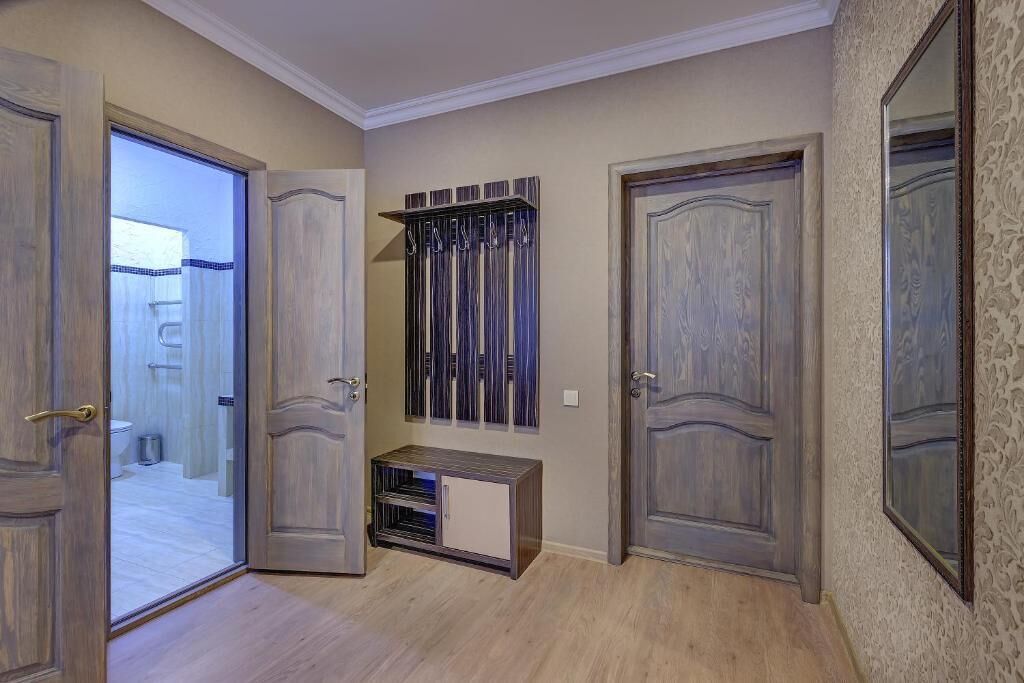 Ein Flur mit zwei Holztüren, einem kleinen Schrank und einem Spiegel an der Wand.