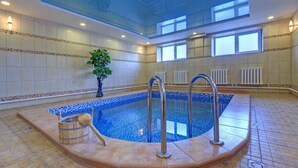 An indoor swimming pool with a tiled floor, a wooden tub, and a plant. - Resident Hotel Almaty (Almaty)