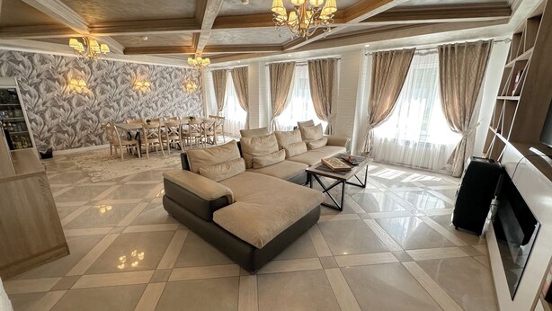 A spacious living area with a large sectional sofa, a dining table with chairs, and a television. - Resident Hotel Almaty (Almaty)