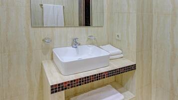A bathroom with a white sink, a mirror, and a tiled backsplash.