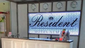 A reception desk with a 'RescAgent' sign, a tiled floor, and a crown emblem above the sign. - Resident Hotel Almaty (Almaty)