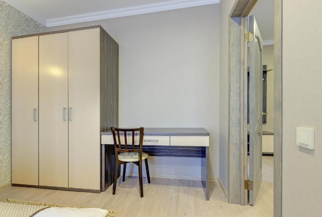 A bedroom with a wardrobe, a desk, and a chair.