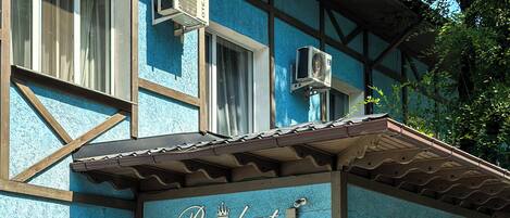 A hotel with a blue facade, a sign reading 'Resident Hotel Almaty,' and two air conditioning units mounted on the exterior wall.