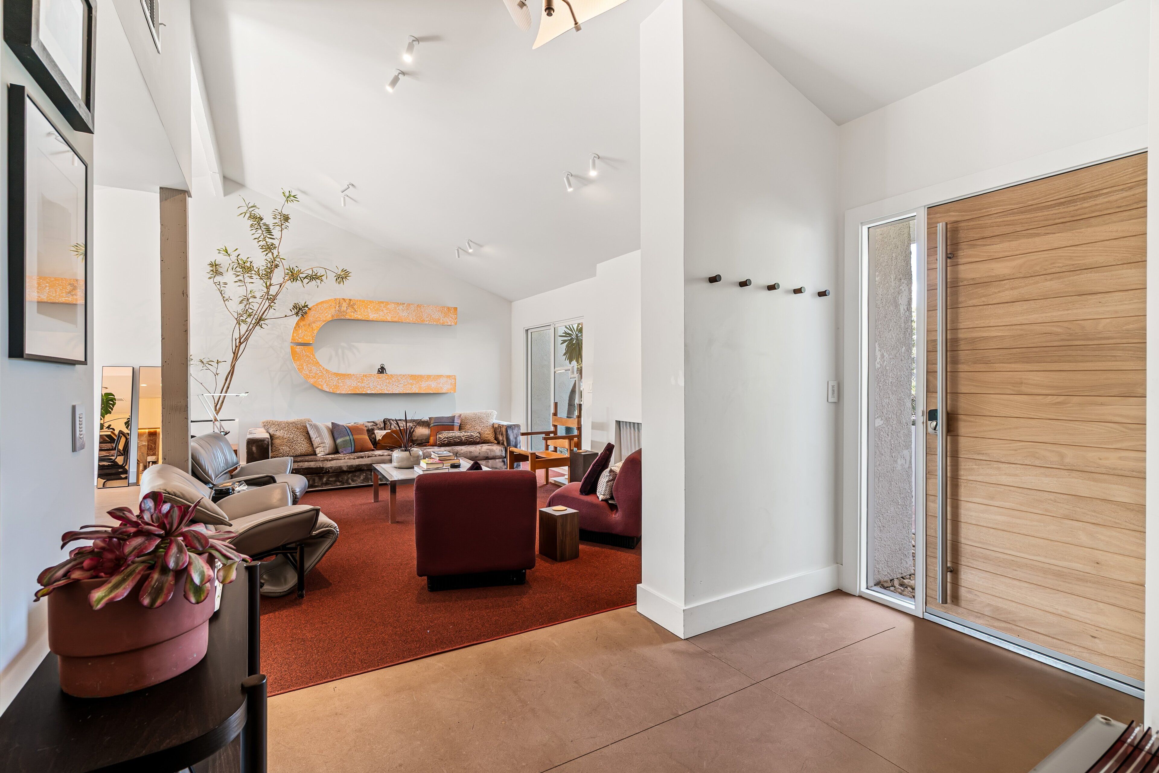 A modern living room with a large C-shaped wall decoration, a red sofa, a coffee table, and a potted plant.