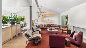 Um espaço de estar moderno com uma grande decoração em forma de C, um sofá, uma mesa de centro e um espaço de jantar com bancada de cozinha.