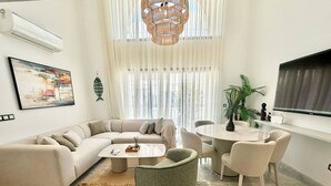 Una sala de estar moderna con un sofá modular, una mesa de centro redonda y un comedor con sillas.